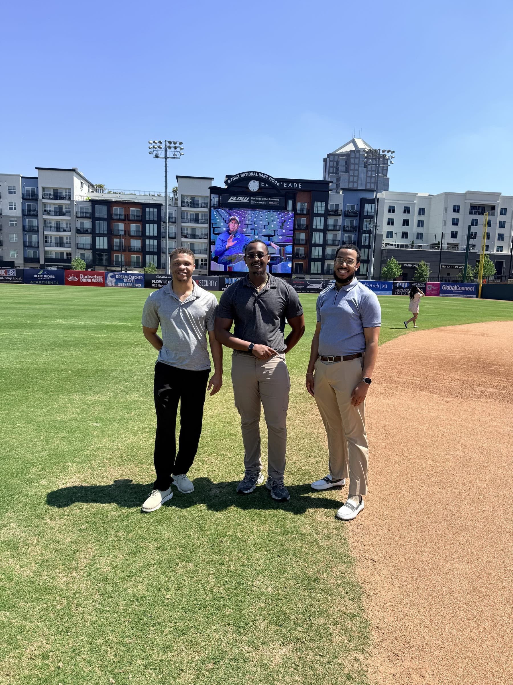 Three young Black men standing together on a ball field in the Triad